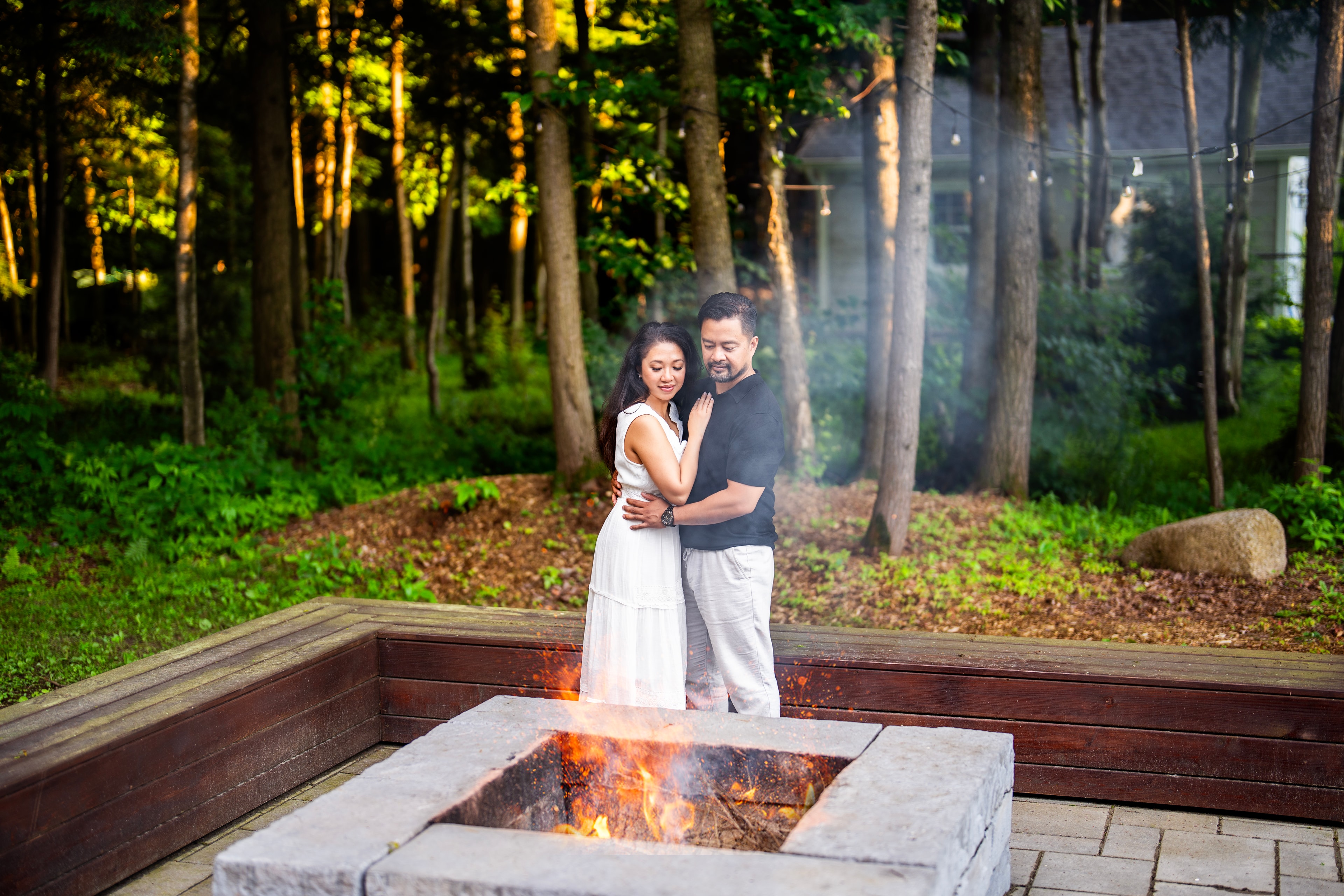 engagement couple embracing fire pit forest evening