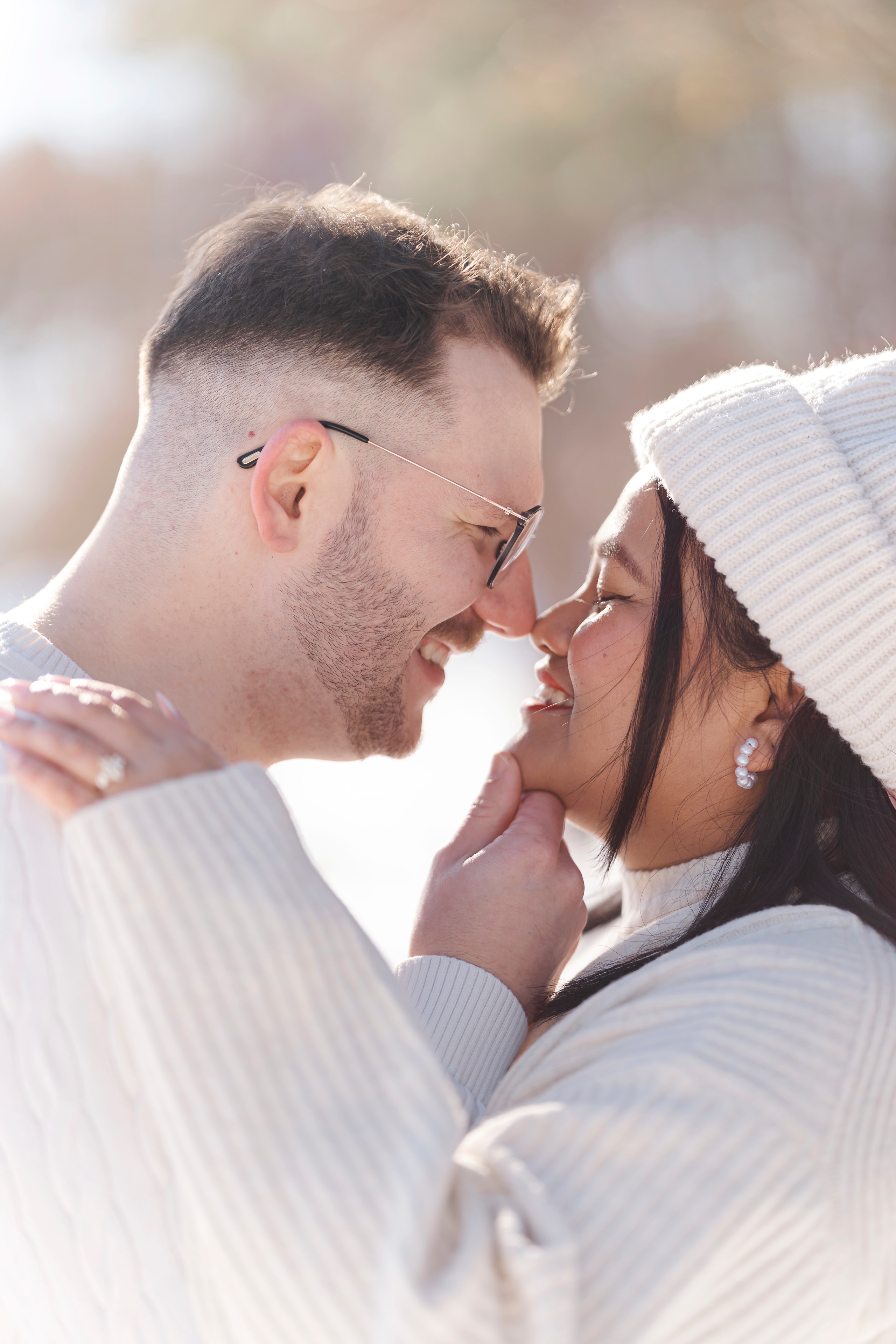 couple nose to nose smiling winter engagement session white sweaters beanie