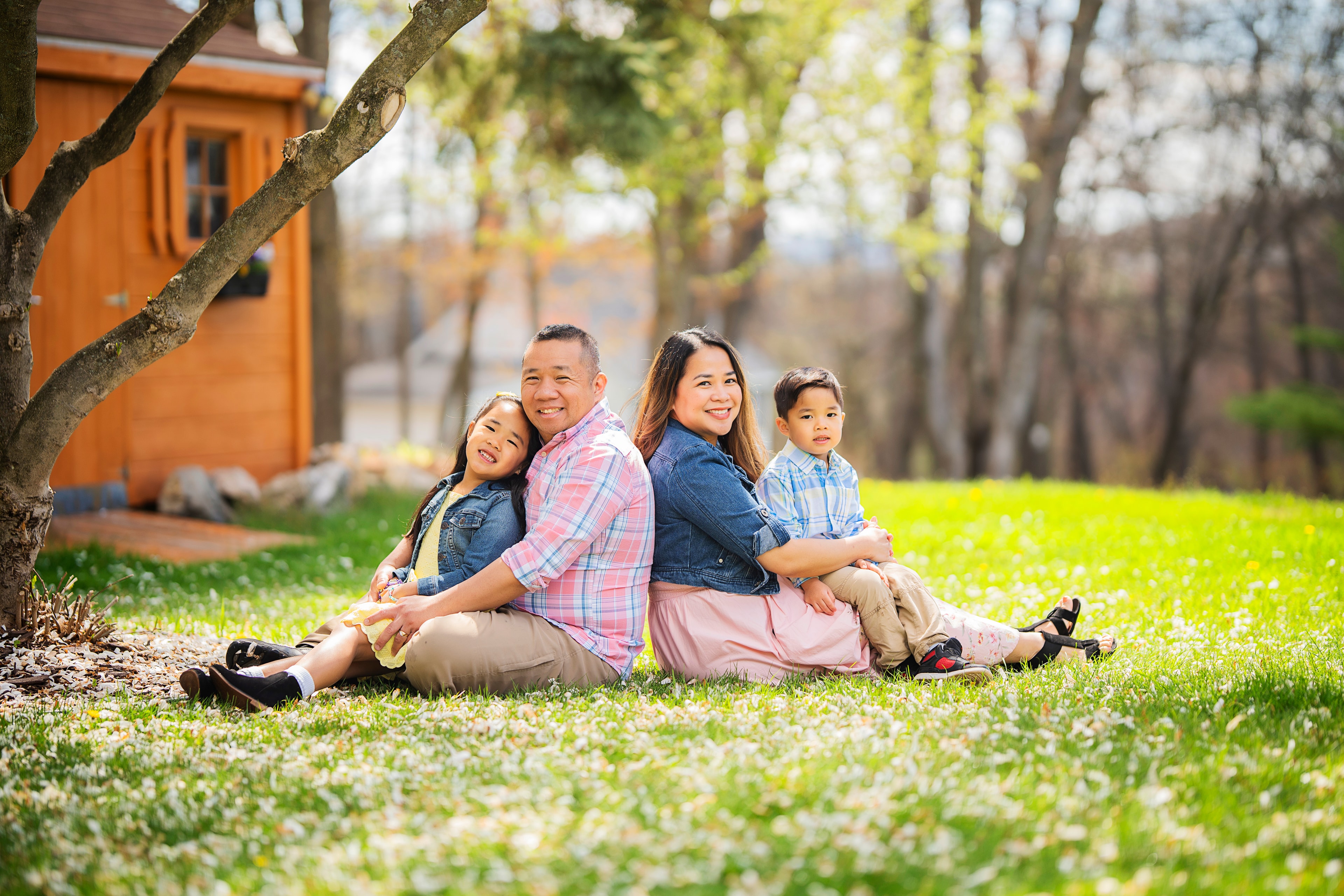 family of four sitting back to back on grass spring garden