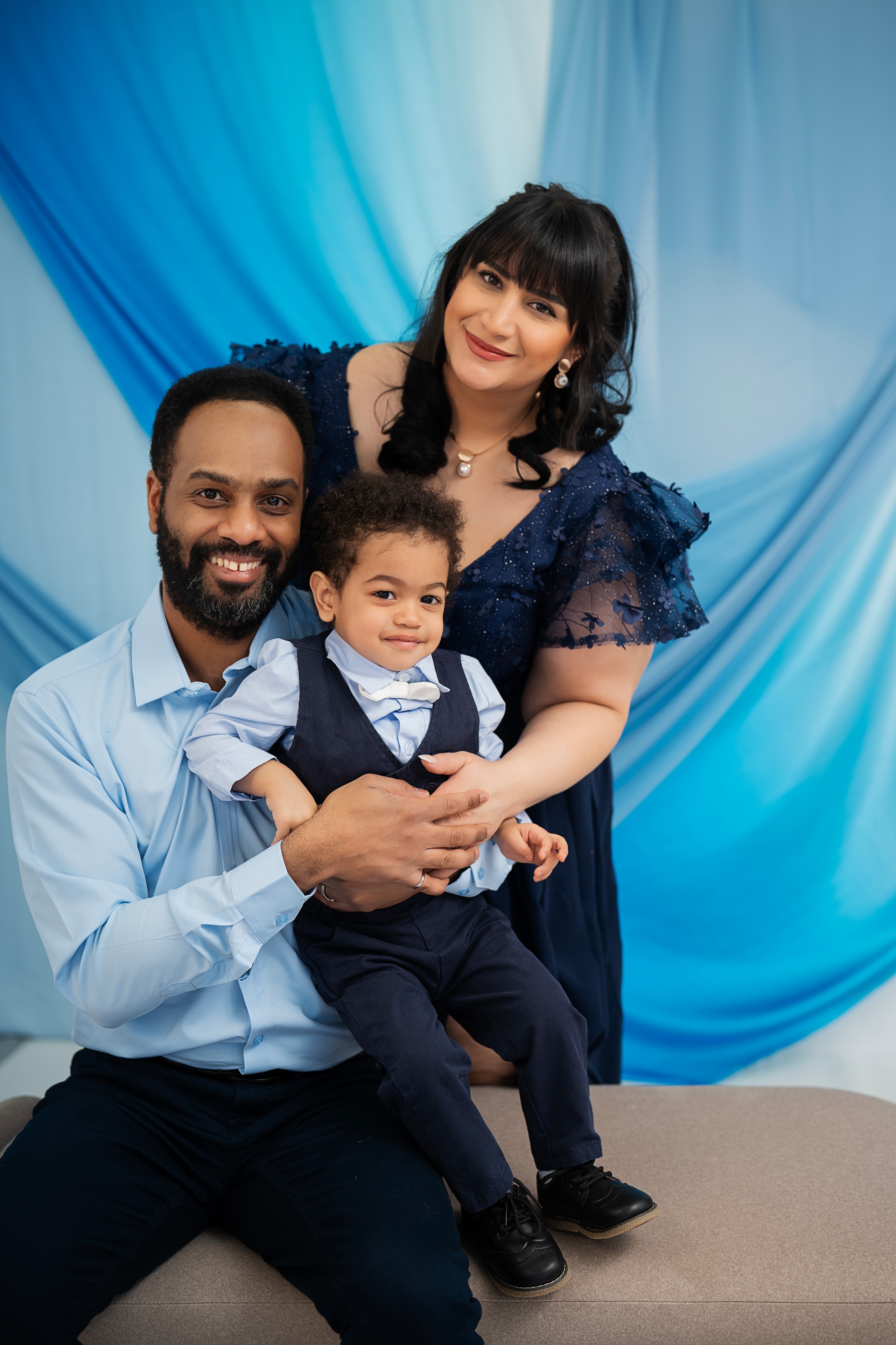 parents with baby in navy blue studio portrait