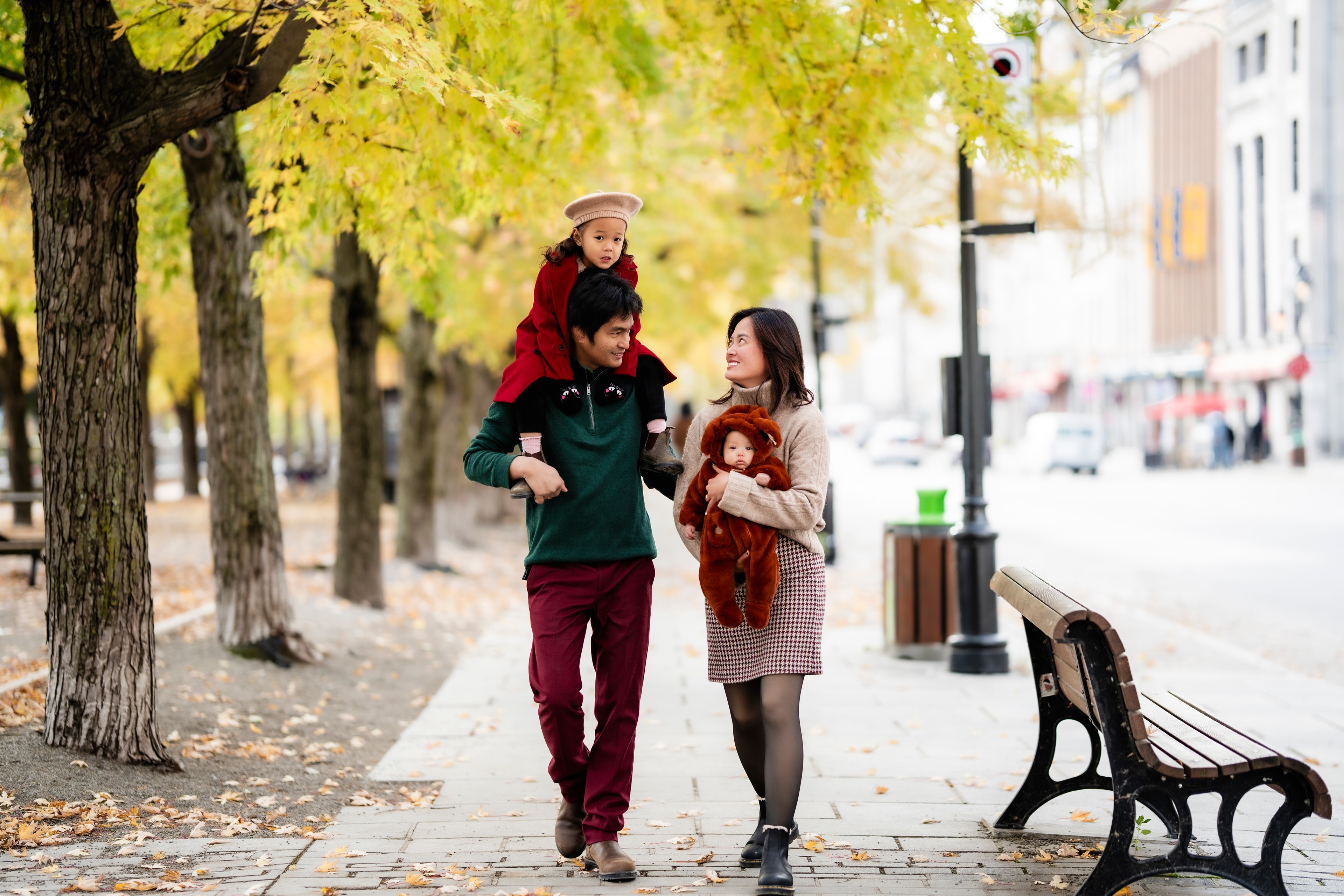 family walking autumn street dad with daughter on shoulders baby in arms
