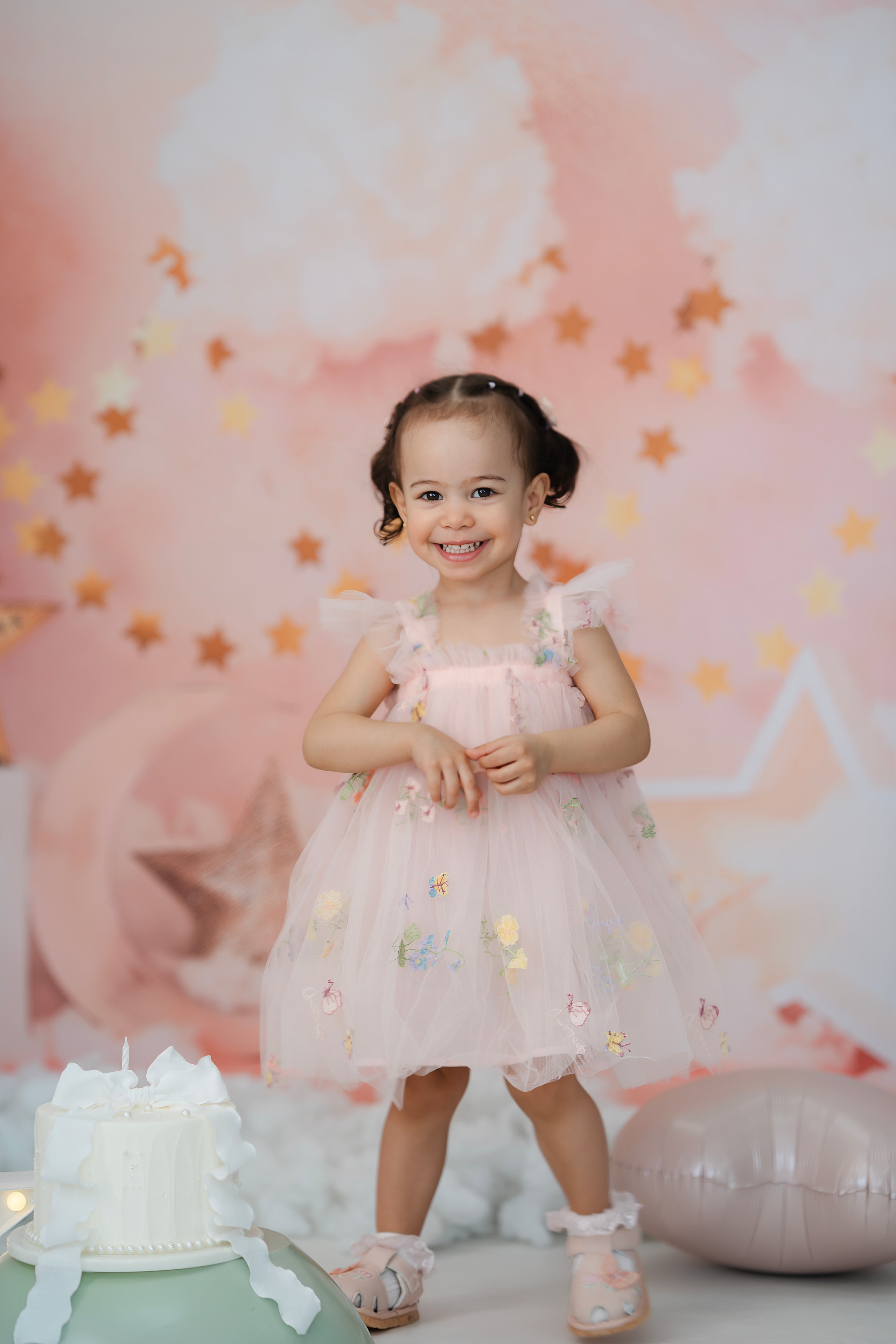 toddler girl in pink tulle dress smiling birthday star backdrop portrait
