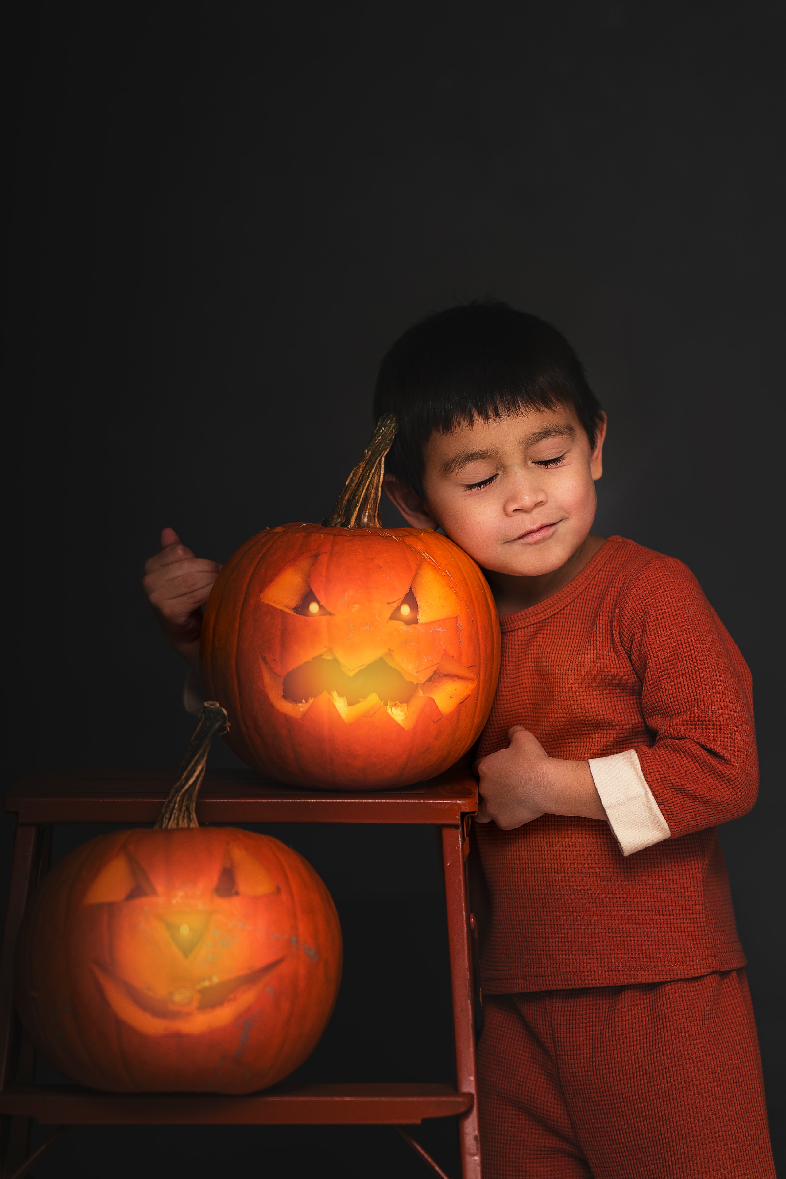 boy in red outfit hugging glowing jack-o-lantern Halloween portrait