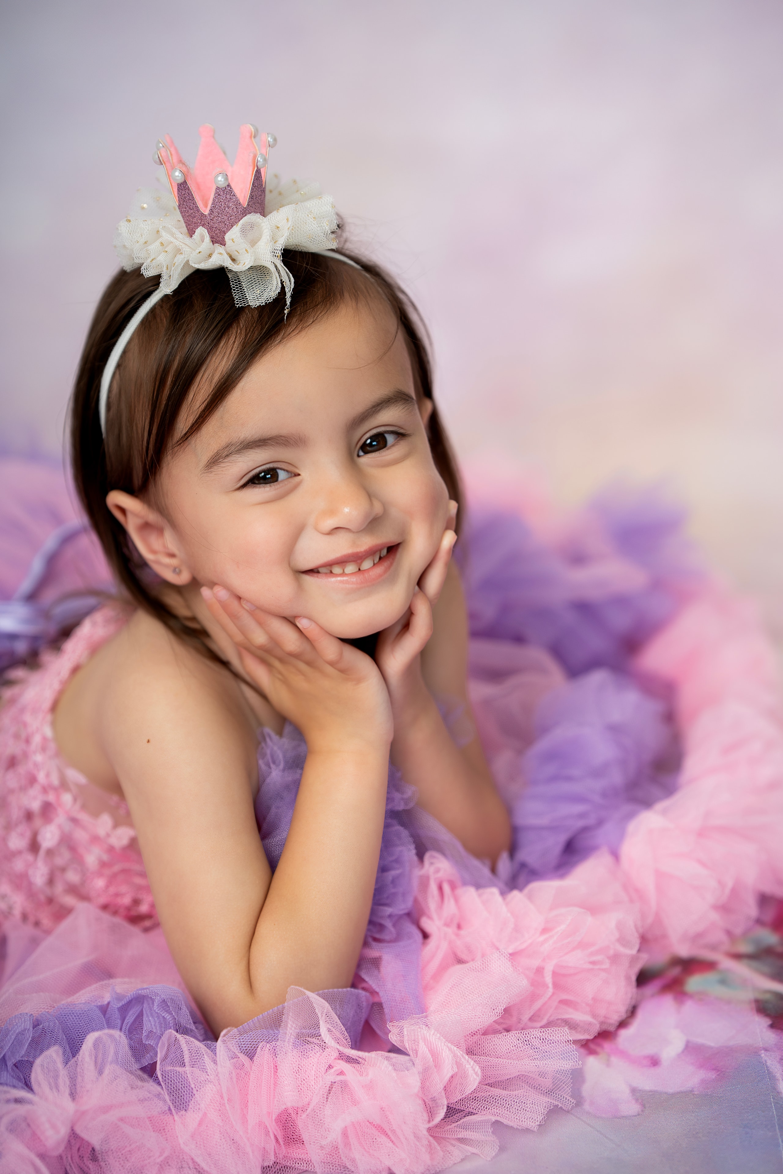 girl in pink princess tulle dress with crown smiling studio portrait
