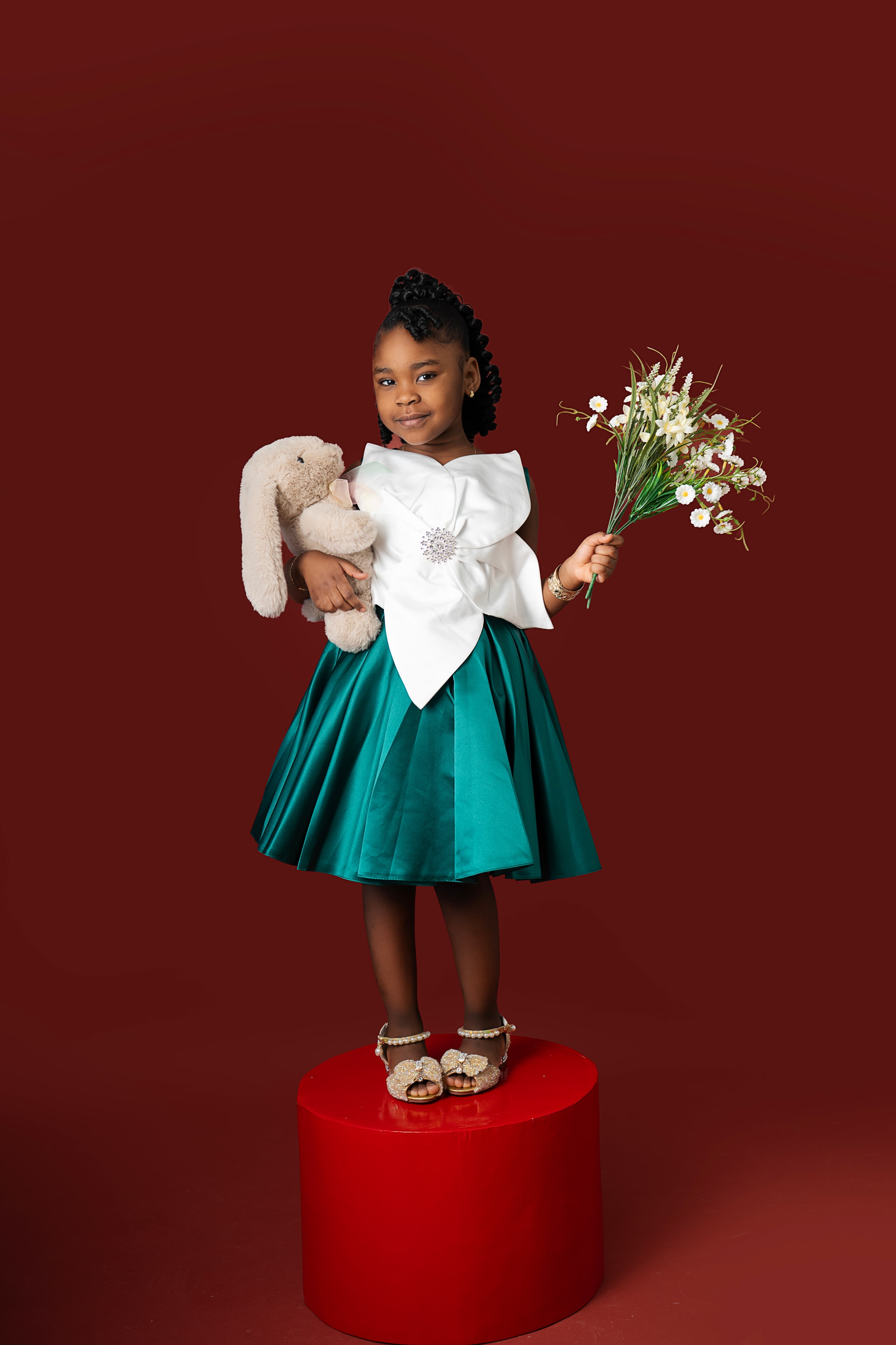 girl in green satin dress holding bunny and flowers burgundy background studio portrait