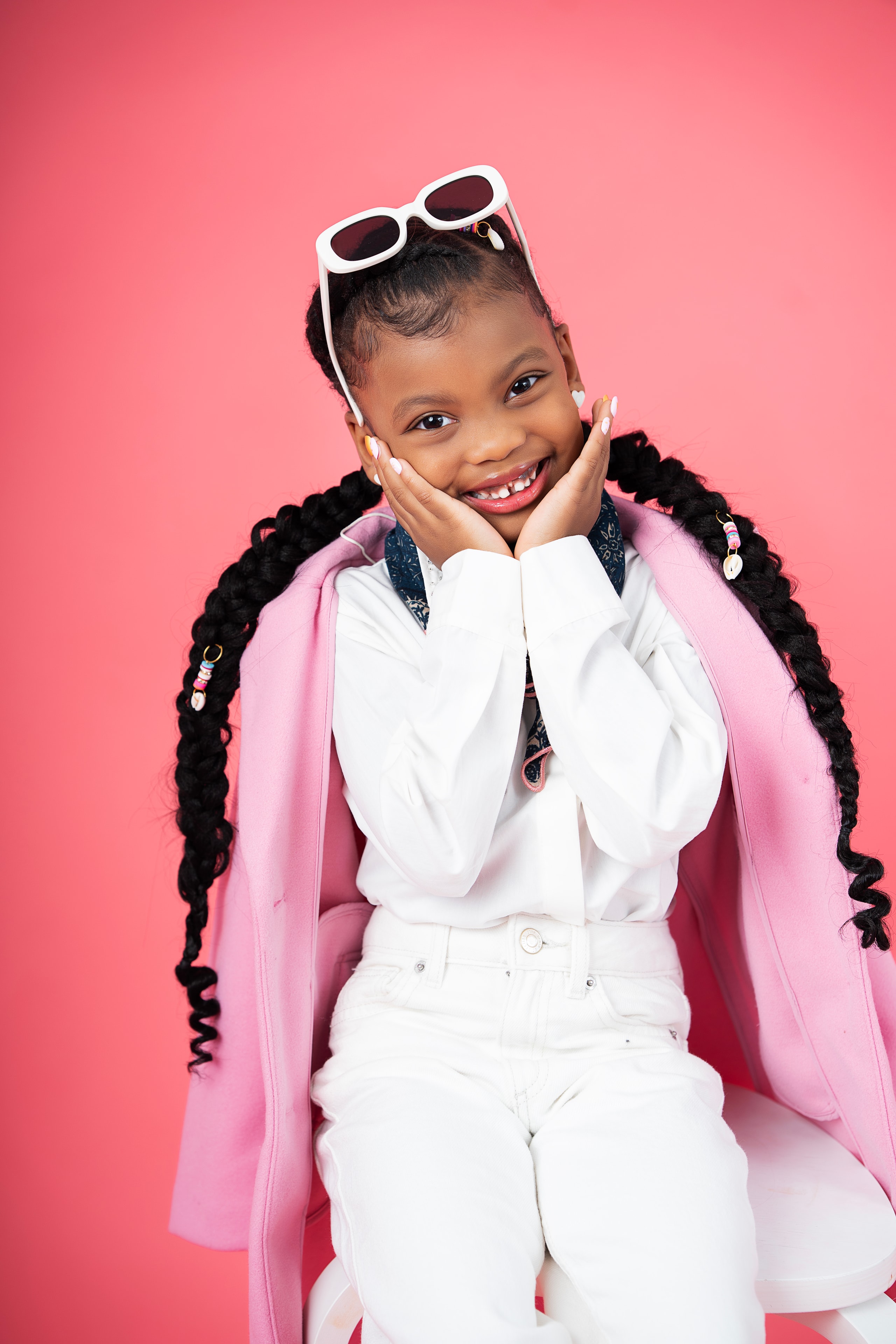 girl in pink blazer white jeans sunglasses smiling pink background portrait