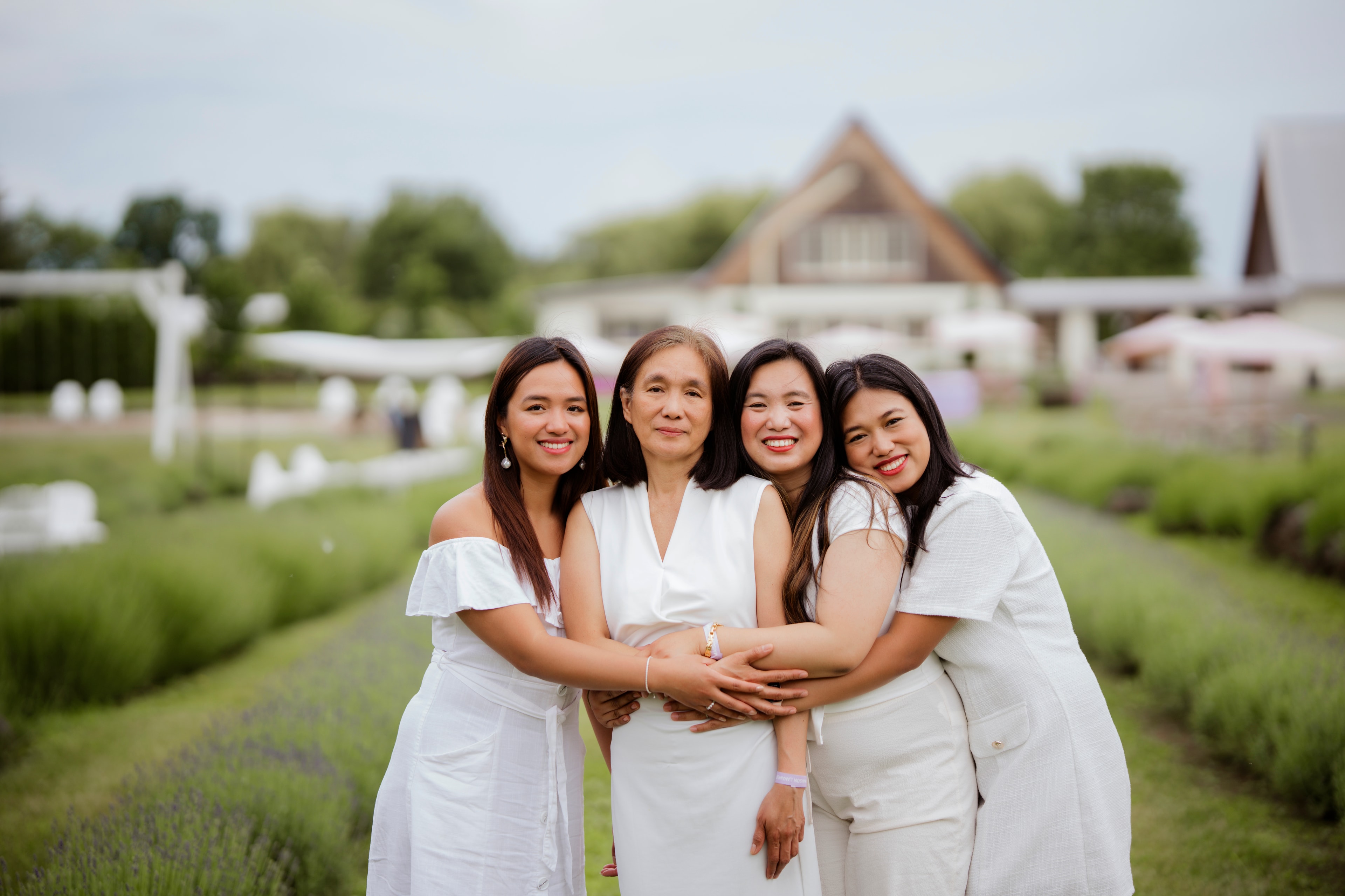 four women mother and daughters in white dresses hugging lavender field